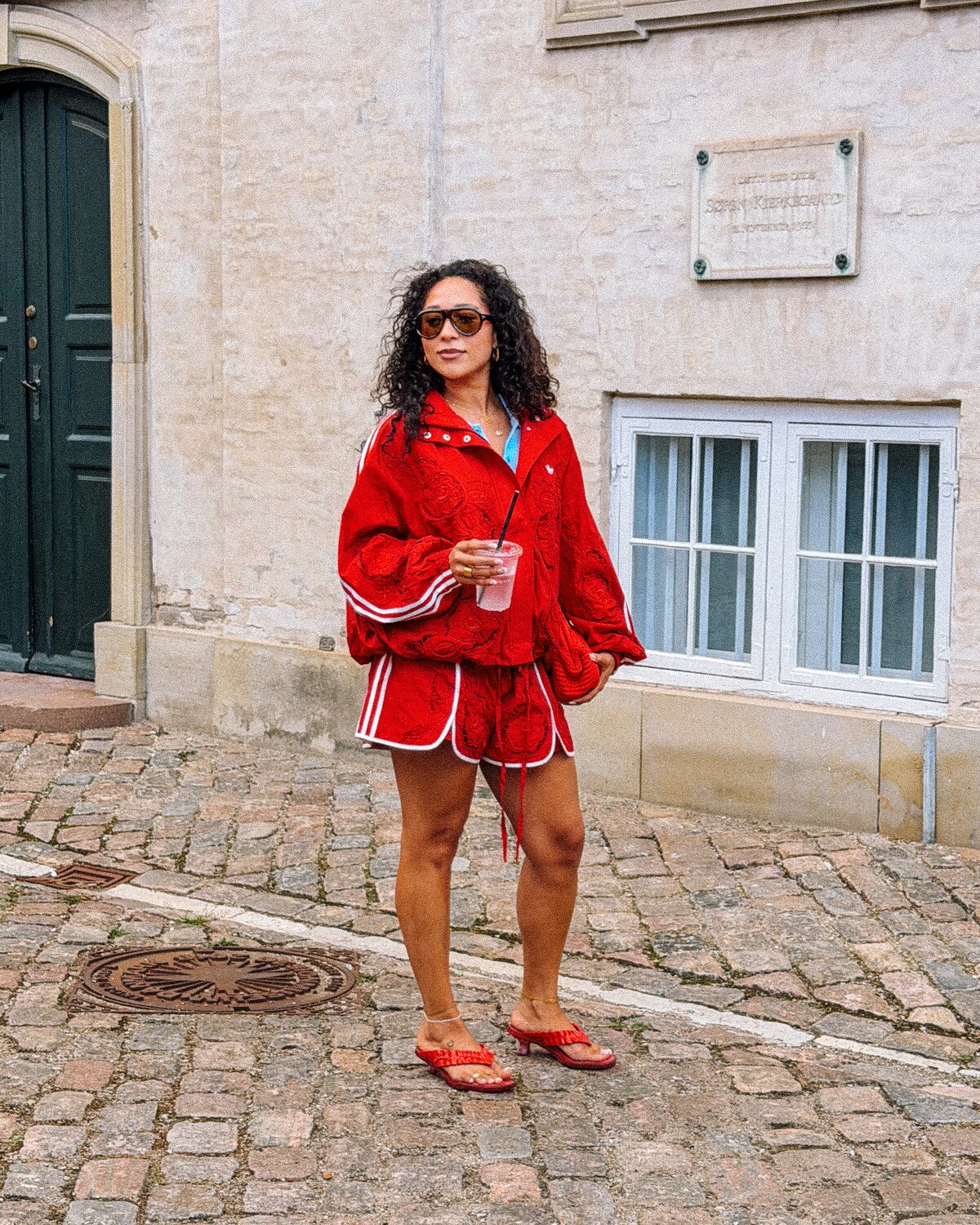 A Copenhagen Fashion Week guest wearing a vivid red matching set and sunglasses