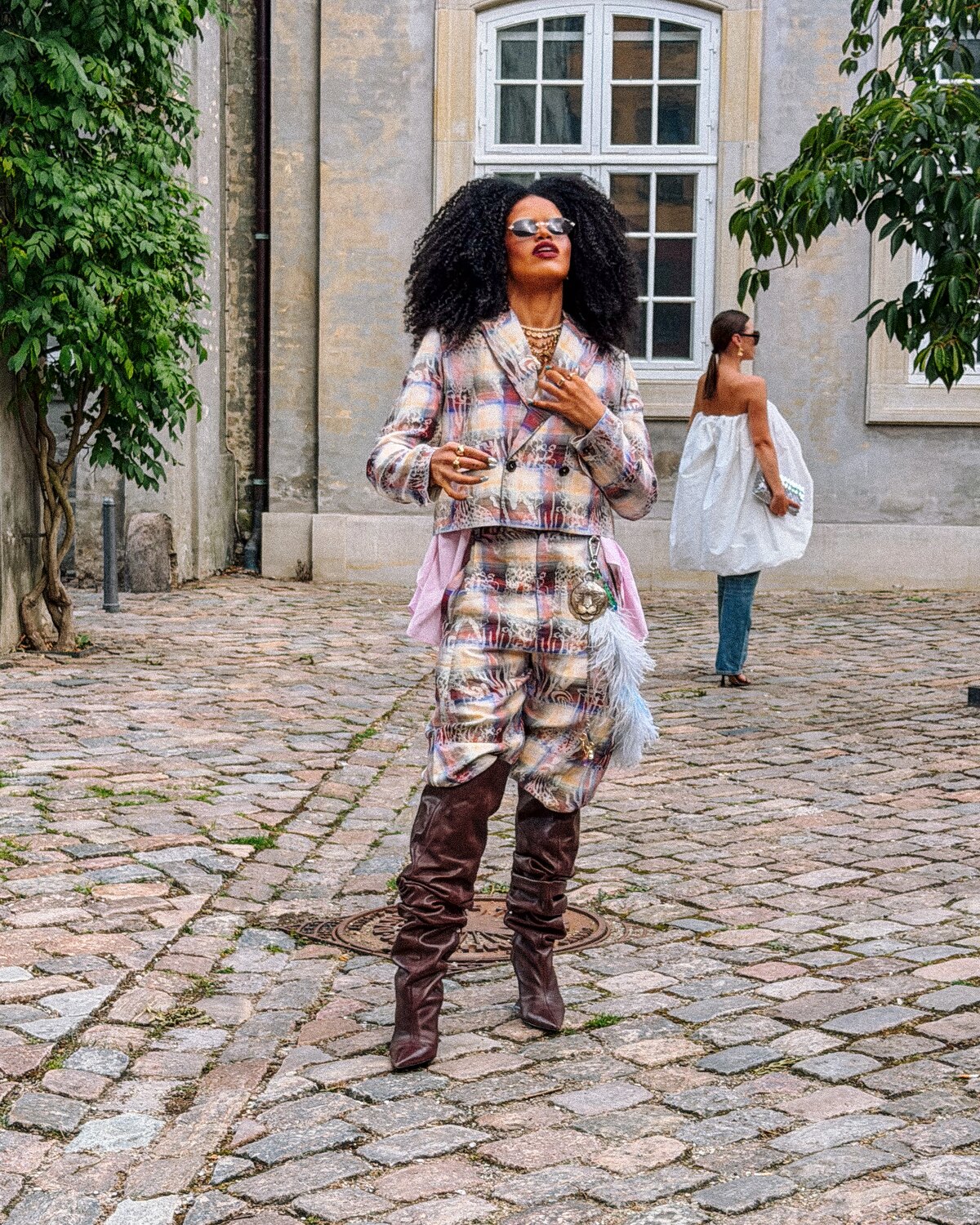 A Copenhagen Fashion Week guest in a layered printed suit and tall brown boots