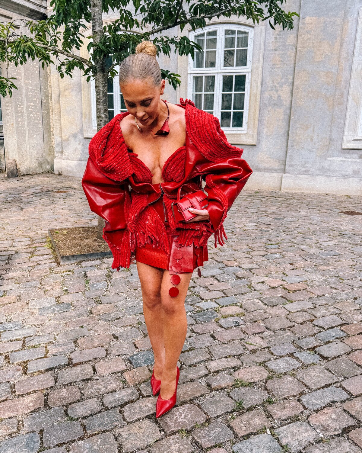A Copenhagen Fashion Week guest wearing a sculptural red look with matching shoes and bag